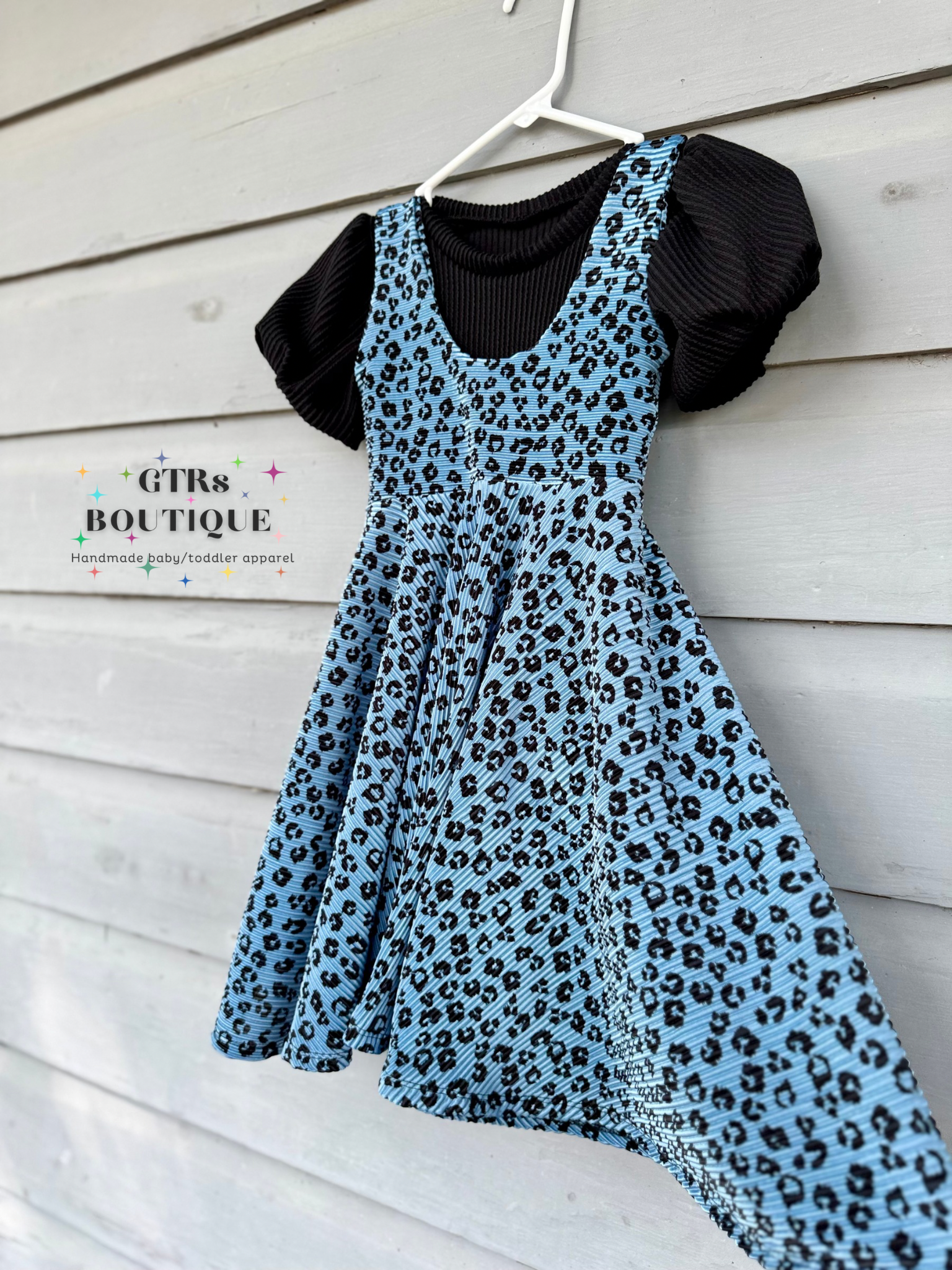 Little girls twirl dress, small black animal print on a blue twirl dress for for little girls, with a black top with puff sleeves layered underneath the twirl dress for little girls
